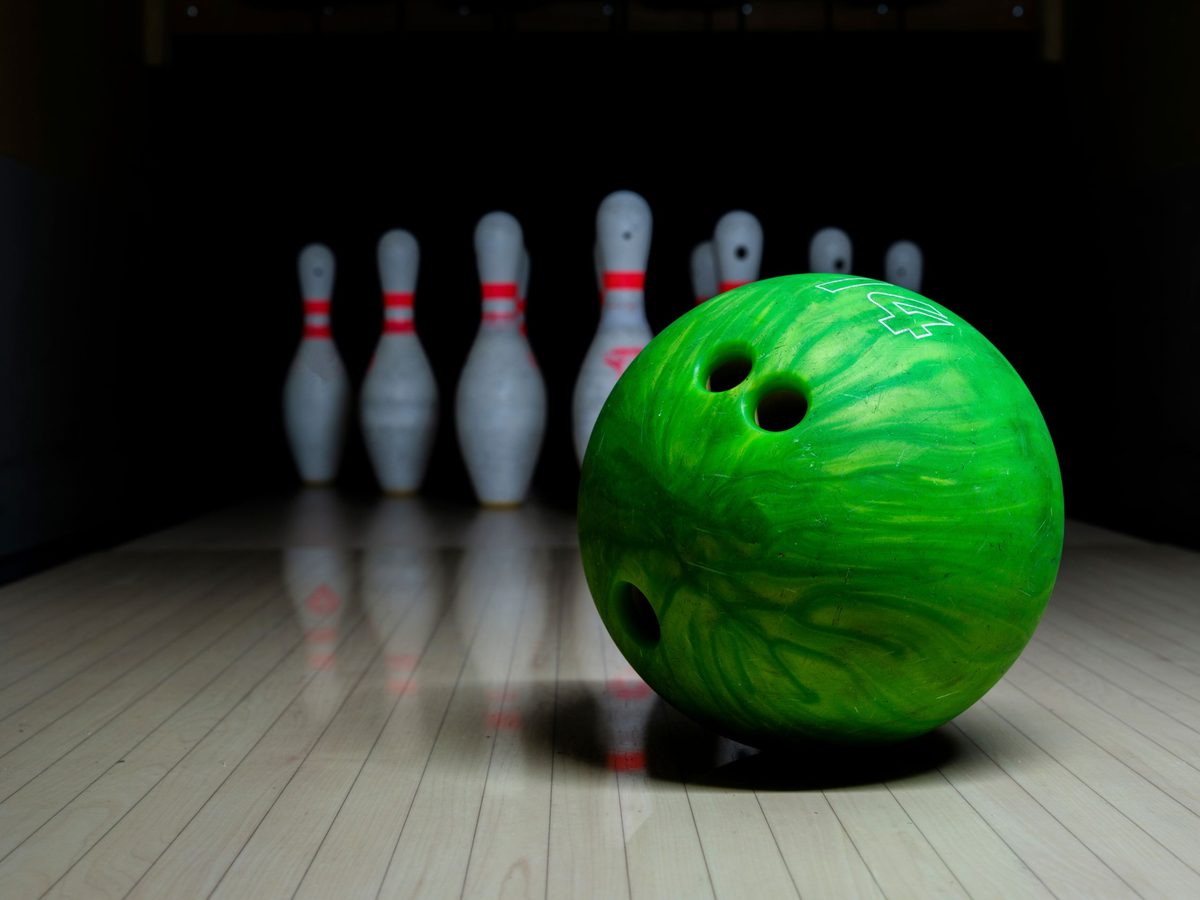 Close-up of a glossy bowling ball on the lane in front of the pins, illustrating the types of bowling balls